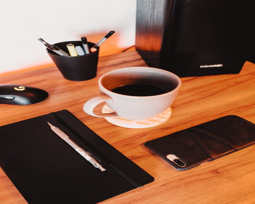 A warm cup of coffee on a modern desk with a notebook and pen, representing communication