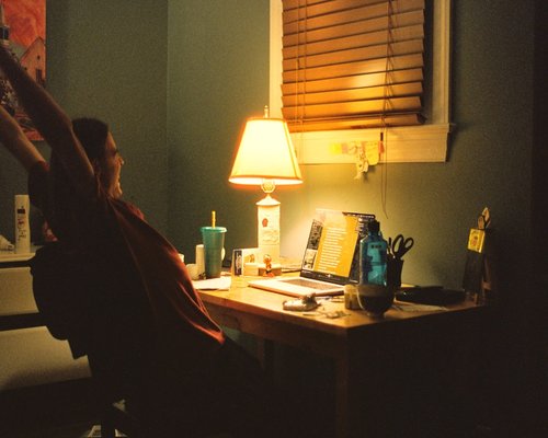 Person adjusting the lamp on their desk for better lighting